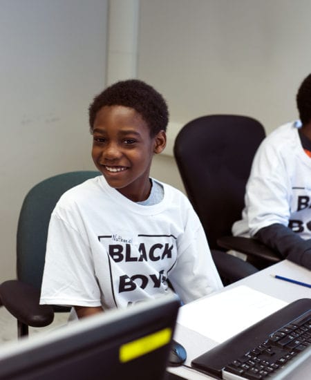 A young male student smiling for picture during a Black Boys Code Workshop.